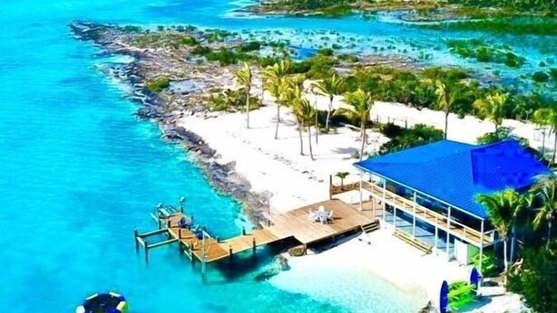 An aerial view of a beach resort with a clear blue sea, a sandy beach, and a building with a blue roof. - Great Location,  beautiful home on the water,beach, pool and top amenities (Georgetown)