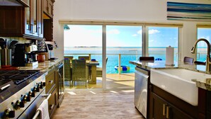 A kitchen with a view of the ocean, a dining area with a table and chairs, and a large window. - Great Location,  beautiful home on the water,beach, pool and top amenities (Georgetown)