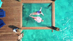 Vista aérea de una terraza de madera con una zona de natación protegida por una red.