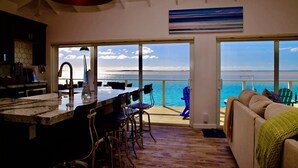 A modern kitchen with a large island, bar stools, and a view of the ocean through large windows. - Great Location,  beautiful home on the water,beach, pool and top amenities (Georgetown)