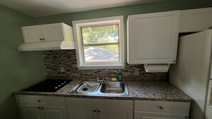 Una cocina con armarios blancos, un lavamanos doble, una ventana con vistas y un salpicadero con un diseño de mosaico.