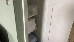 Een smalle gang met een witte deur aan de rechterkant en een groene wand aan de linkerkant.