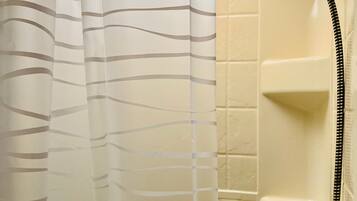 A bathroom with a shower, a white tiled wall, and a striped shower curtain.