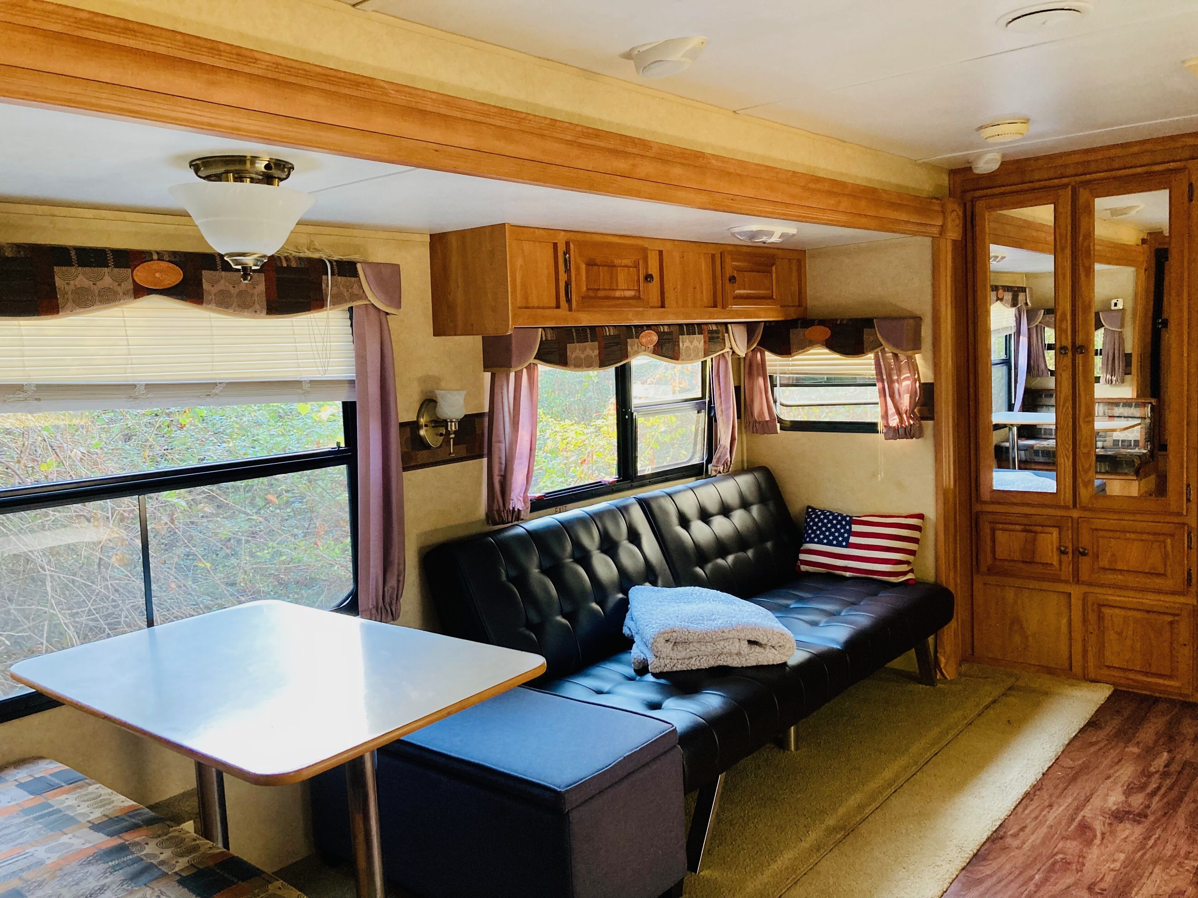 Un intérieur de camping-car chaleureux et confortable, avec un canapé, une table et des placards en bois.