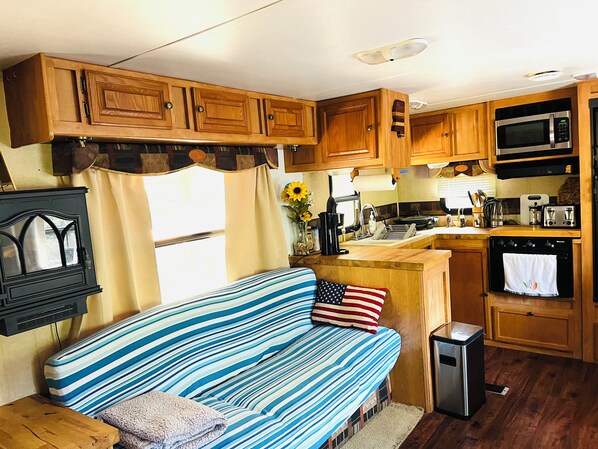 A compact RV kitchen with wooden cabinets, a microwave, a sink, and a stove.