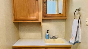 A bathroom with wooden cabinets, a sink with a soap dispenser, and a towel hanging on a metal towel ring.