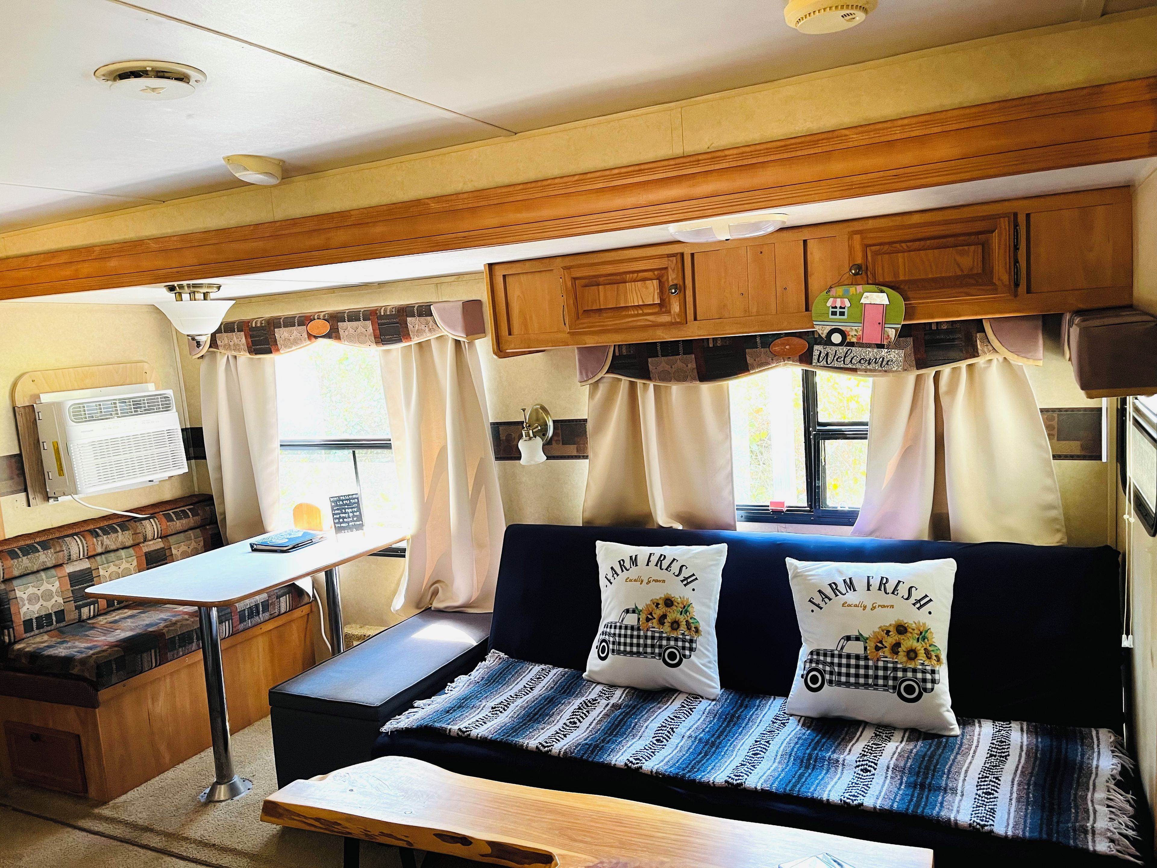 Een gezellig RV-interieur met een kitchenette, een eethoek en een zithoek met twee kussens met landelijke motieven.