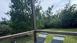 A wooden deck with metal loungers and a metal grill.