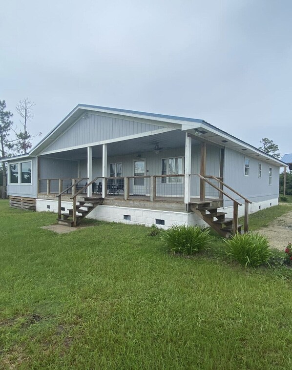 A single-story house with a covered porch and a small set of wooden stairs leading to the entrance.