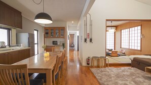 Una cocina moderna con armarios de madera, un comedor con mesa y sillas de madera, y una sala de estar acogedora con sofá y ventana.