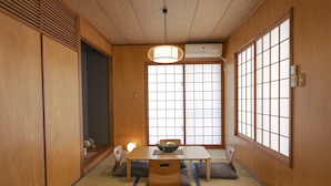 Una habitación japonesa tradicional con suelo de tatami, una mesa baja con cojines y puertas correderas shoji.