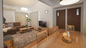Una sala de estar moderna con sofá, televisión, mesa de comedor y sillas.