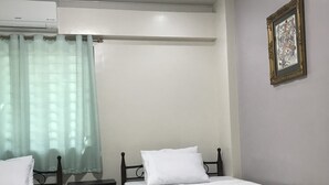 Una habitación con dos camas individuales, una mesita de noche, un armario pequeño y un aire acondicionado.