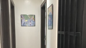 Un pasillo con una puerta al final, una obra de arte enmarcada en la pared y un portón negro.