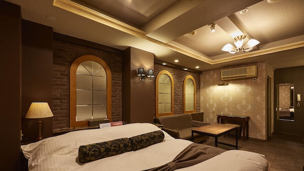 A hotel room with a large bed, two armchairs, a small table, and a ceiling fan. - Hotel Christmas (Inazawa)