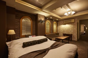 A hotel room with a large bed, two armchairs, a small table, and a ceiling fan. - Hotel Christmas (Inazawa)