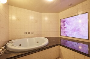 A modern bathroom with a freestanding bathtub, a large mirror, and a wall-mounted TV displaying a floral pattern. - Hotel Christmas (Inazawa)