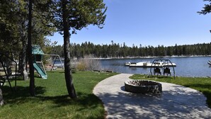 A park with a playground, a concrete path, a fire pit, and a lake with boats.