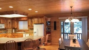 A wooden cabin interior with a kitchen, dining area, and a large window. - Limelight Lodge-Waterfront-Boat Dock-WiFi (Fremont County)
