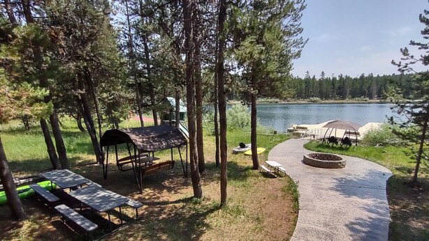 A lakeside deck with picnic tables and a covered seating area, surrounded by trees and overlooking a lake. - Limelight Lodge-Waterfront-Boat Dock-WiFi (Fremont County)