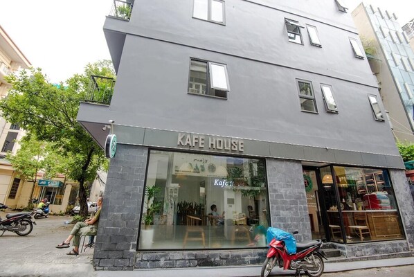 Una cafeteria anomenada "Kafe House" amb un disseny modern, grans finestres i una zona d'exterior visible per als clients.