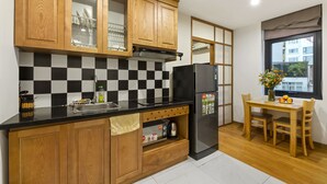 Eine moderne Küche mit Holzausstattung, einer schwarzen Arbeitsplatte, einem Edelstahlkühlschrank und einem Essbereich mit Holztisch und Stühlen.