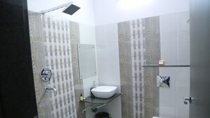 A bathroom with a white sink, a toilet, and a shower area. - Hotel Saraogi Palace (Gaya)