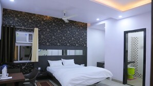 A modern hotel room with a bed, desk, chair, and a small table with a kettle. - Hotel Saraogi Palace (Gaya)