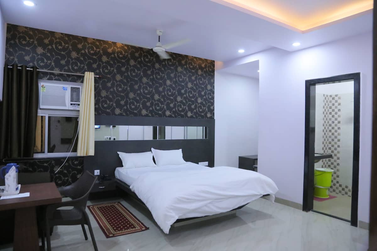 Quarto de hotel moderno com cama, escrivaninha, cadeira e uma pequena mesa com chaleira.
