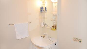 A bathroom with a white sink, a towel rack, a mirror, and shelves with toiletries.