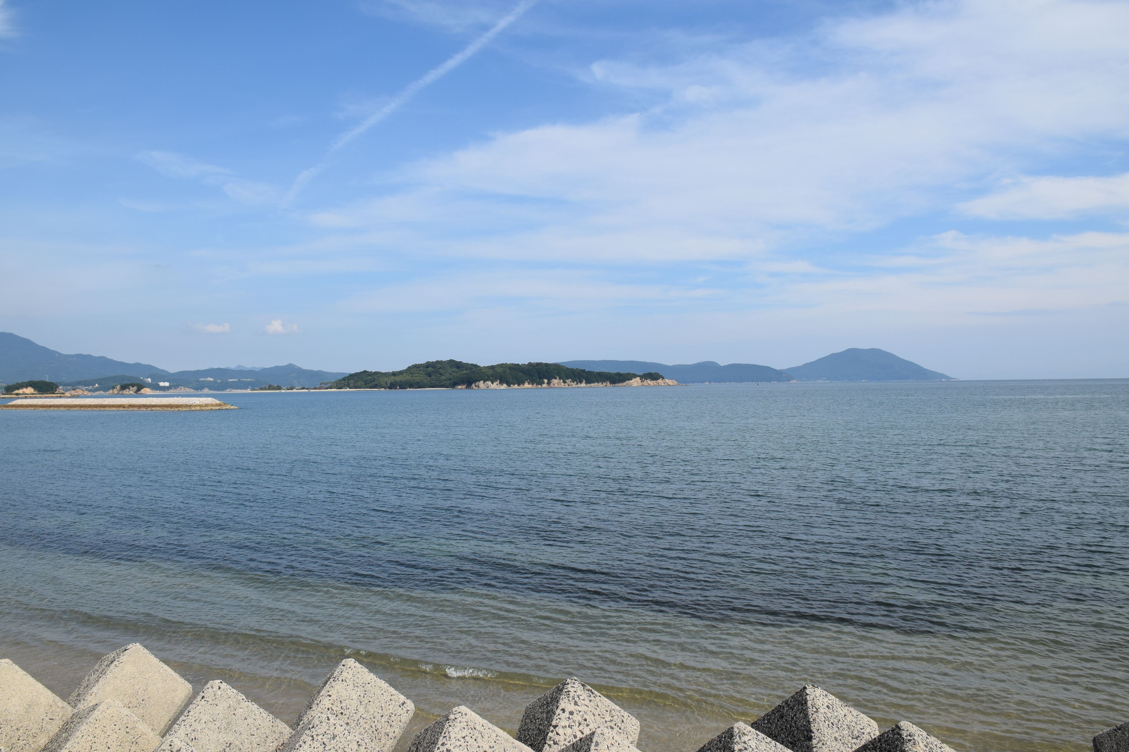 A calm body of water with a distant island and mountains.