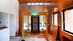 Un intérieur en bois avec un sol en pierre, un comptoir d’accueil et un extincteur.