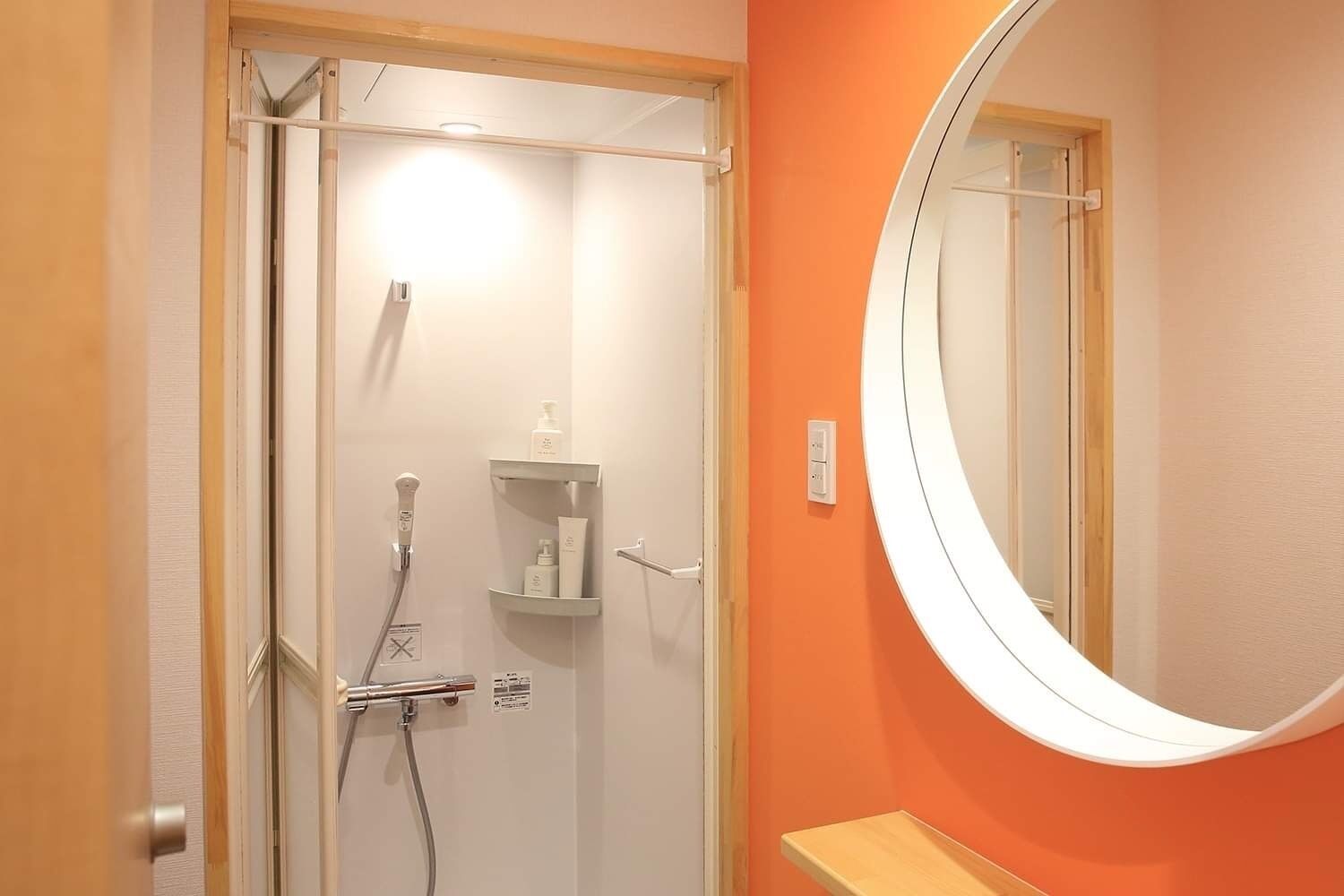 A bathroom with a glass shower door, a white sink, and a round mirror.
