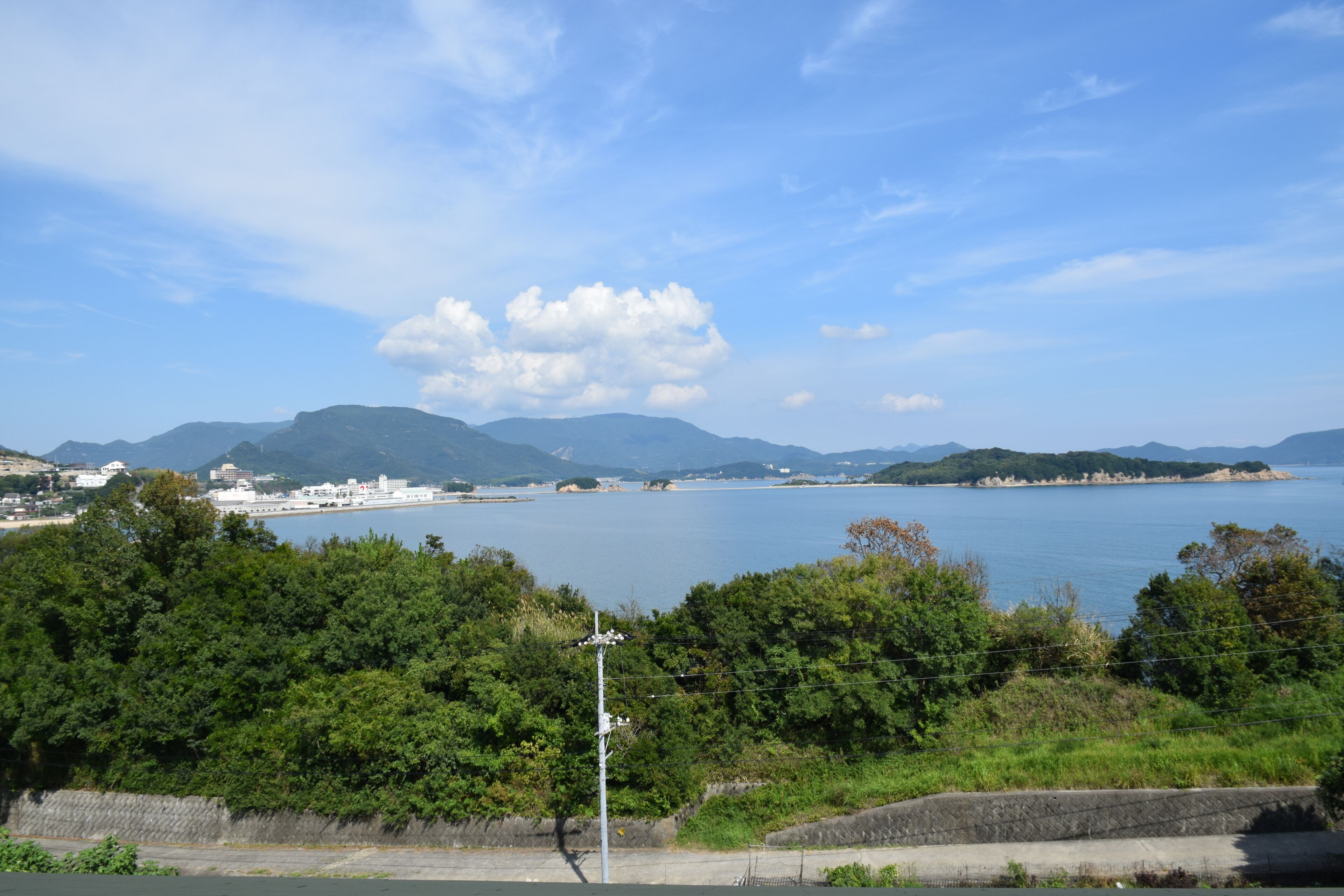 A coastal landscape with a body of water, mountains, and greenery.
