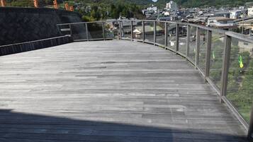 A wooden deck with a glass railing overlooking a town.