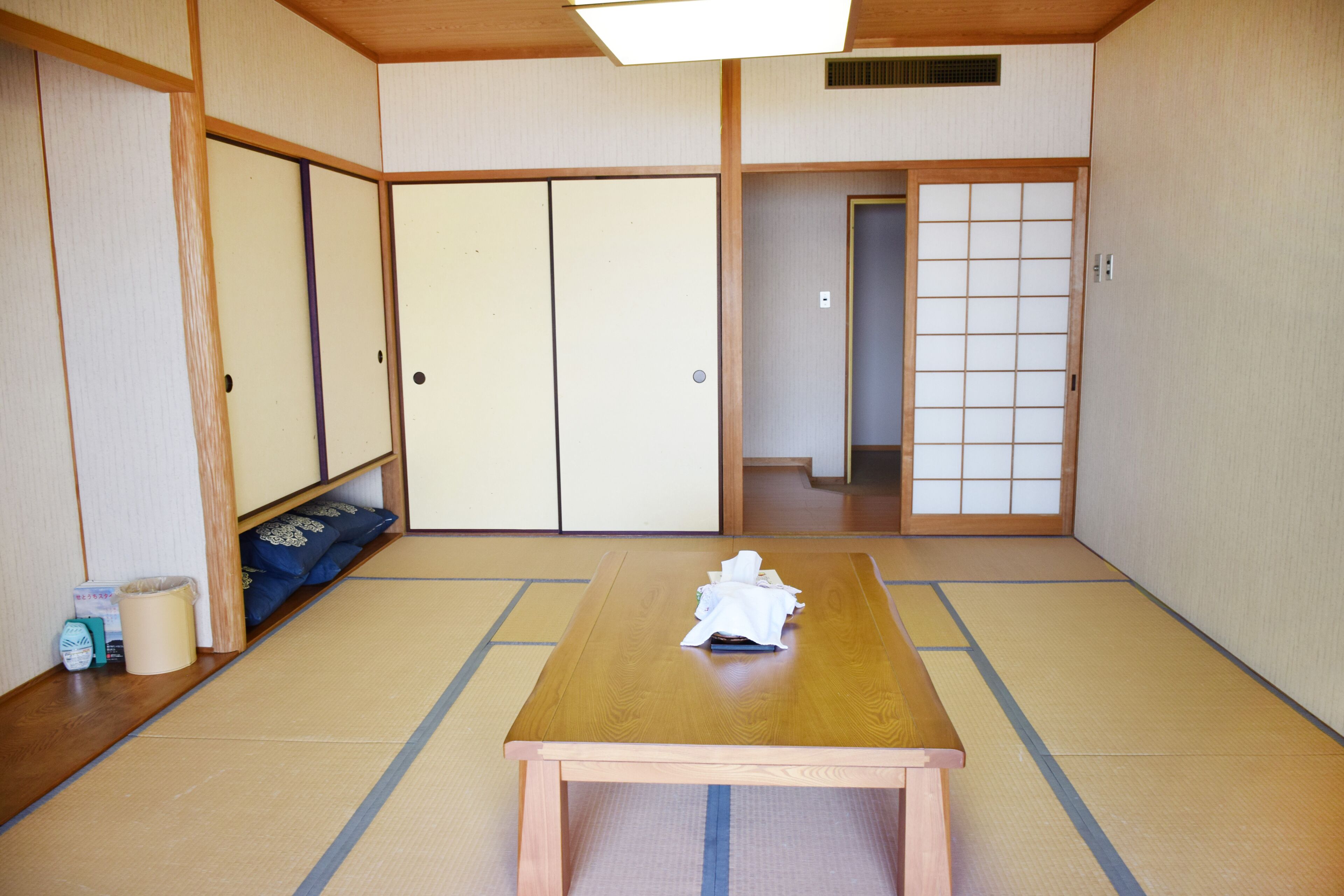 A traditional Japanese room with tatami flooring, a wooden table, and sliding doors.