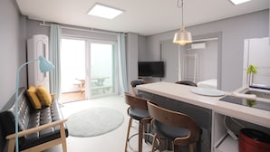 Una cocina moderna con una isla central, taburetes de bar, una mesa de comedor y televisor integrado.