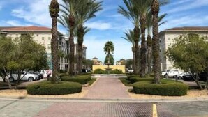 A pathway flanked by palm trees leading to a building with a tiled roof. - Tidecrest 144 · 3 Suites Near Convention, Universal, Disney (Orlando)