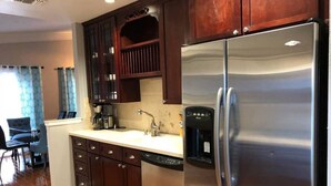 A kitchen with dark wooden cabinets, a stainless steel refrigerator, a coffee maker, and a dishwasher. - 6149 Sandcrest · Next TO Universal. 8 Beds. Pool. Very Clean (Orlando)