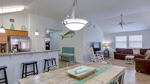 Une cuisine moderne équipée d’appareils électroménagers en acier inoxydable, une table à manger en bois et un banc vert.