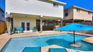 Une piscine avec des chaises longues et un espace patio couvert.