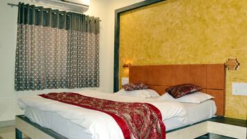A bedroom with a bed, a nightstand, a wall-mounted light, and a window with curtains.