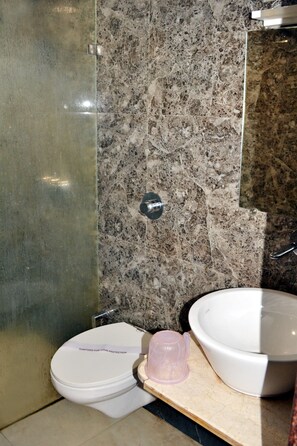Un bagno con parete in marmo, un water, un lavabo e zona doccia.