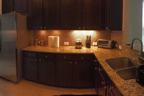 A kitchen with dark wooden cabinets, a granite countertop, a stainless steel refrigerator, a toaster, and a sink. - 10 Beds! Modern House. Universal & Convention (Orlando)
