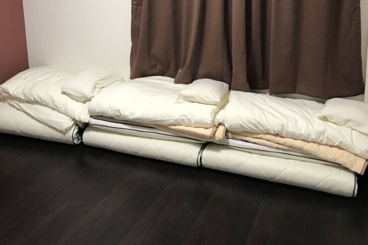 A room with a bed, brown curtains, and a white wall.