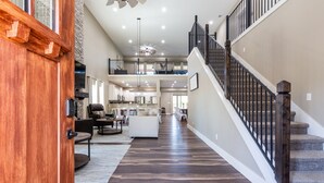 A spacious interior with a central staircase, a kitchen area, and a living room with a fireplace.