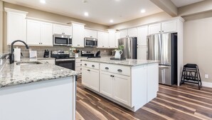 A modern kitchen with white cabinets, stainless steel appliances, and a granite countertop.