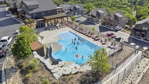 A residential area with a swimming pool surrounded by houses, a covered patio, and a view of a lake.