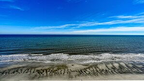 Een strand met golven en een heldere lucht.
