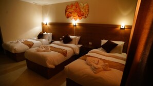 A hotel room with three beds, each with a wooden headboard, white linens, and brown throw blankets. - Petra Aretas Hotel (Wadi Musa)